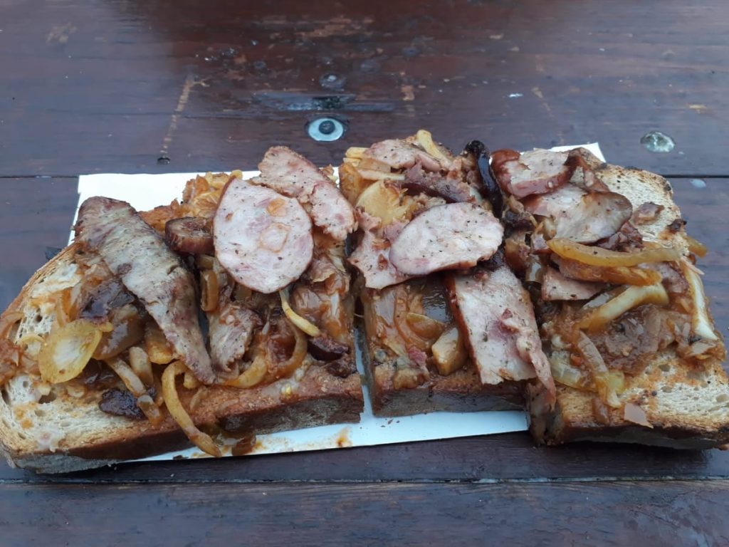 Rebanada de pan con salchicha tipica polaca y cebolla caramelizada comprada en el mercadillo navideño en Cracovia