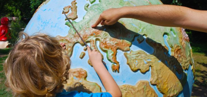 Un niño en frente de un globo enseña Polonia en el mapa
