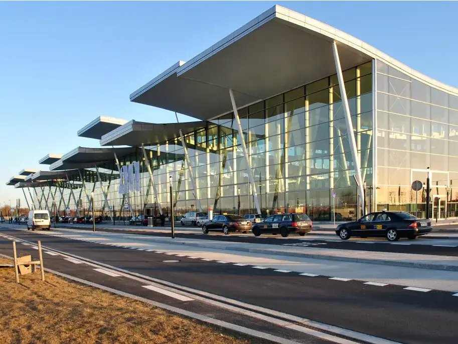 Exterior de la terminal del Aeropuerto de Breslavia con taxis frente a su fachada acristalada