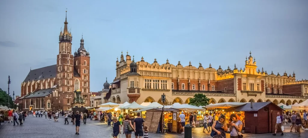 Plaza del Mercado de Cracovia al anochecer, con la basílica de Santa María y la Lonja de los Paños