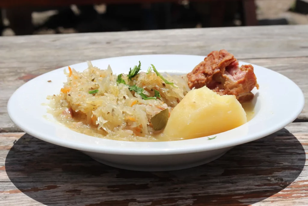 Plato de chucrut con patata cocida y carne, una comida tradicional de la gastronomía polaca