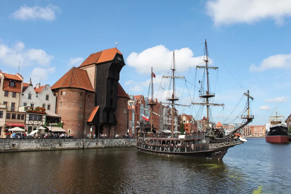 Barco turístico frente a la grúa medieval de Gdansk, a orillas del río Motława