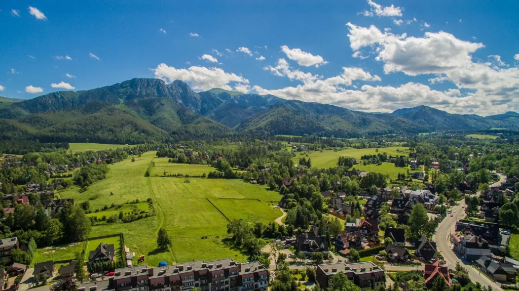 Vista aérea de Zakopane con prados, casas tradicionales y los montes Tatras al fondo
